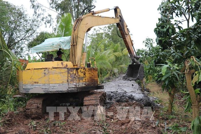 Phương tiện cơ giới gia cố đê bao bảo vệ vùng sản xuất nông nghiệp ở xã Mỹ An Hưng, tỉnh Đồng Tháp trước mùa lũ. Ảnh: Hữu Chí - TTXVN