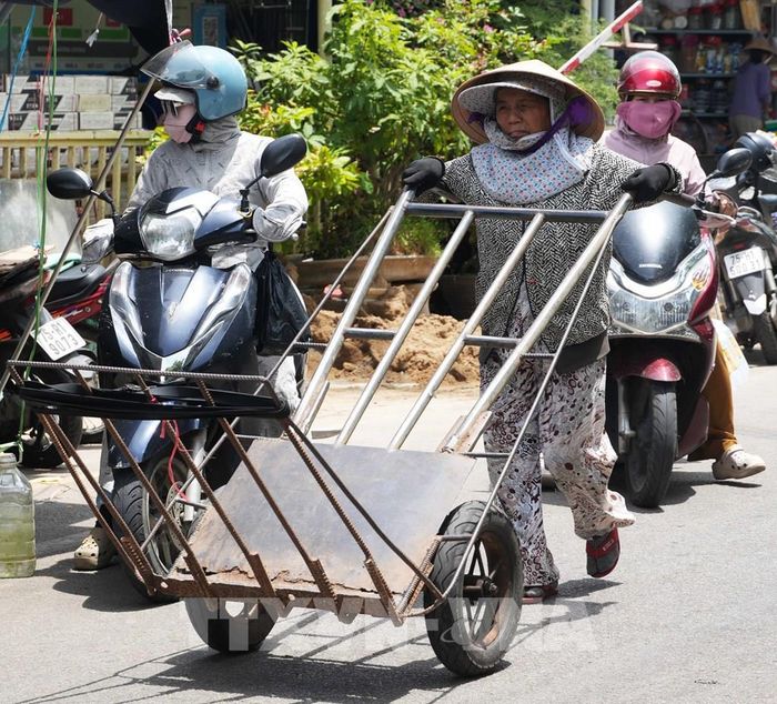 Vất vả di chuyển xe đẩy hàng hóa trên đường Chương Dương - chợ Đông Ba, thành phố Huế dưới trời nắng nóng. Ảnh: Nguyên Lý - TTXVN 