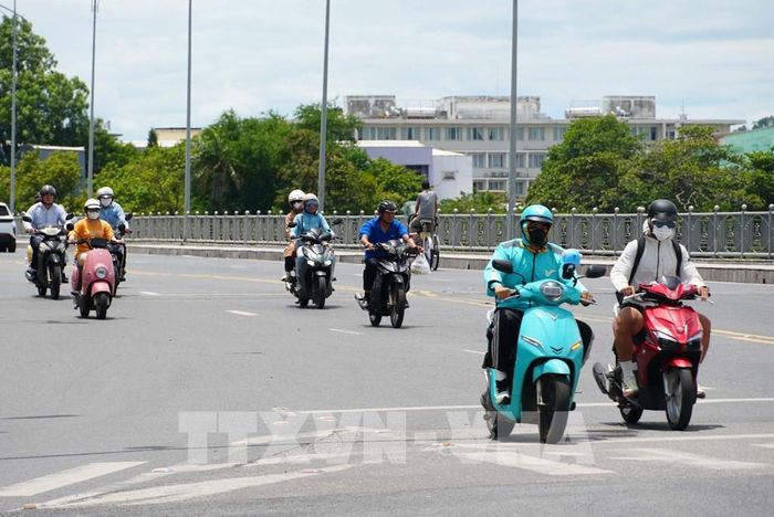Người dân tham gia giao thông trên cầu Phú Xuân, thành phố Huế, mặc đồ bảo hộ để giảm tác động nắng nóng. Ảnh: Nguyên Lý - TTXVN
