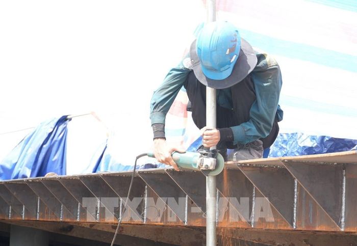 Công nhân trên công trường sửa chữa đập Thảo Long, thành phố Huế, đội thêm mũ rộng vành để giảm tác động nắng nóng. Ảnh: Nguyên Lý - TTXVN