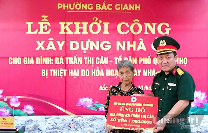 Đại diện Ban Chỉ huy Quân sự phường Bắc Gianh trao biển hỗ trợ cho gia đình bà Trần Thị Câu - Ảnh: N.M