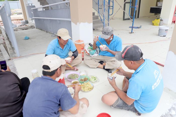 Không kịp rời công trường giữa ca, nhiều công nhân mang cơm theo, tranh thủ dùng bữa ngay tại công trình rồi tiếp tục làm việc.