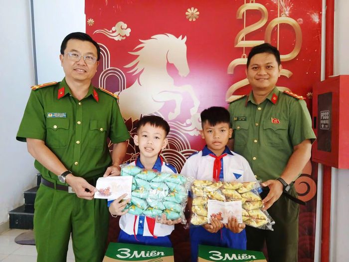 Thượng tá Trần Khải Điền, Trưởng Công an phường Xuân Đài (bên phải), cùng đồng đội trao quà cho hai học sinh tiểu học trong mô hình "Con nuôi Công an phường".