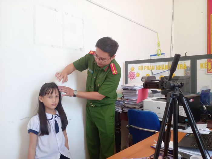 Cán bộ Công an phường Xuân Đài chỉnh sửa tóc để làm định danh điện tử cho một học sinh tiểu học ở địa phương. Ảnh: Hữu Toàn.