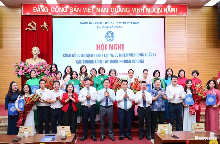 Lãnh đạo phường Đống Đa trao Quyết định và tặng hoa chúc mừng Ban Giám hiệu các trường sau sắp xếp. Ảnh: Hoa Thành