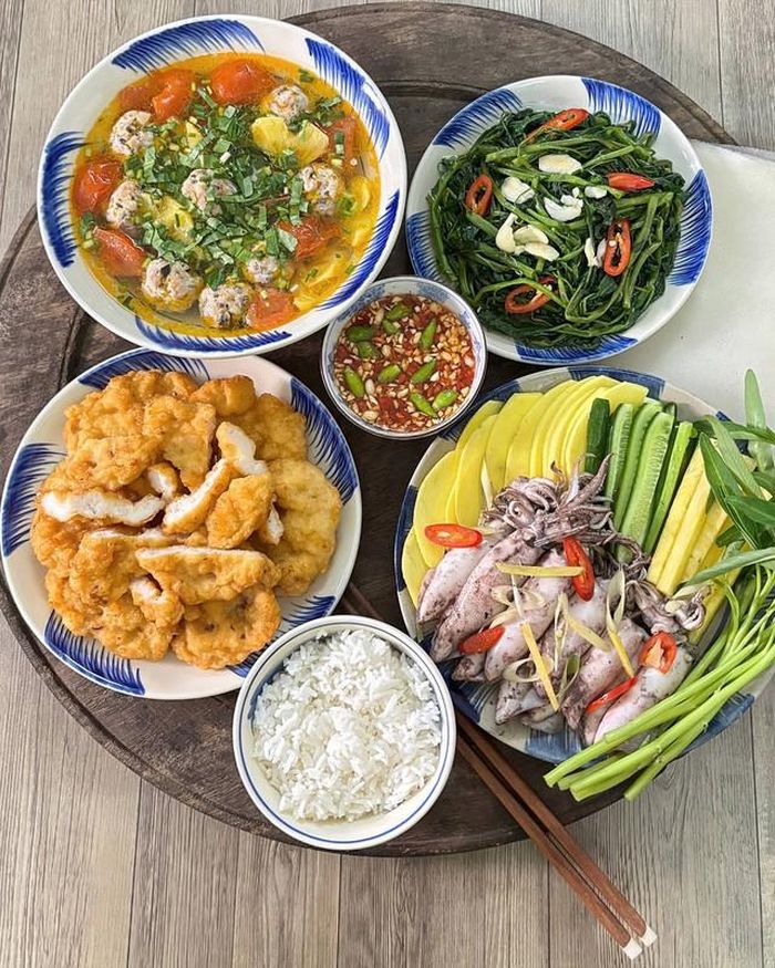 Mực luộc vừa chín tới được cuốn cùng bánh tráng, xoài xanh, dưa chuột và rau thơm, chấm mắm chua ngọt tỏi ớt. Chả mực Hạ Long chiên vàng ruộm, dai giòn ăn kèm. Bát canh chua mọc nấu dứa có vị chua dịu, ngọt thanh, trong khi rau muống xào tỏi giúp mâm cơm thêm tròn vị.