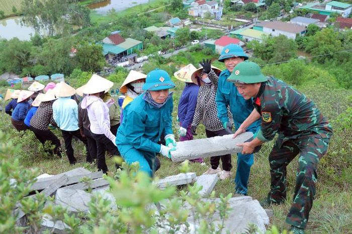 Cán bộ, chiến sĩ và người dân phối hợp vận chuyển vật liệu đến khu vực thi công dòng chữ “BÁC HỒ SỐNG MÃI”. Ảnh: H.Huệ.