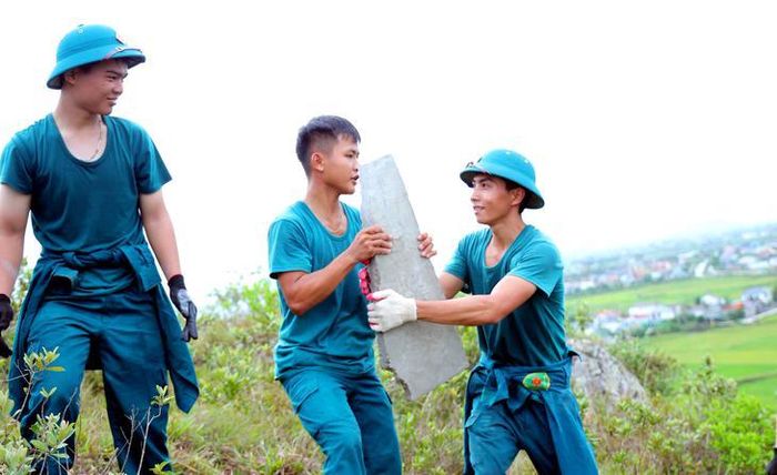 Các lực lượng chuyền tay từng tấm bê tông trên địa hình dốc của núi Nhón. Ảnh: H.Huệ.