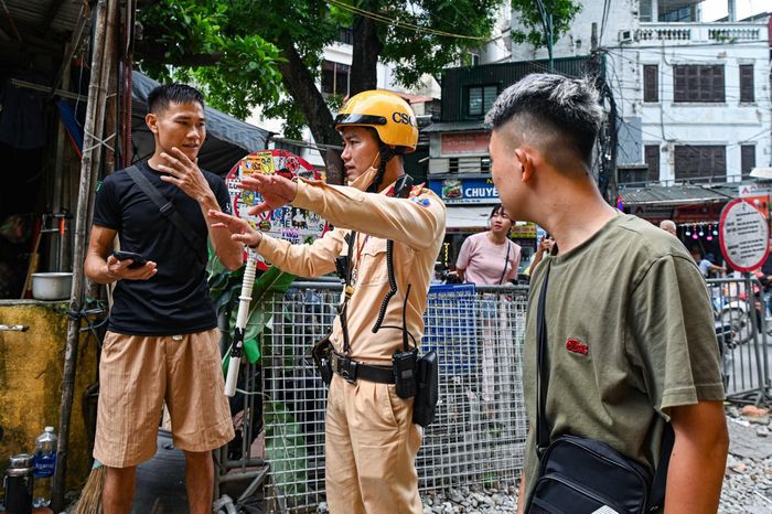 Cảnh sát giao thông nhắc nhở du khách đảm bảo an toàn tại "phố cà phê đường tàu" Hà Nội, sáng 11/8. Ảnh: Đan Châu.