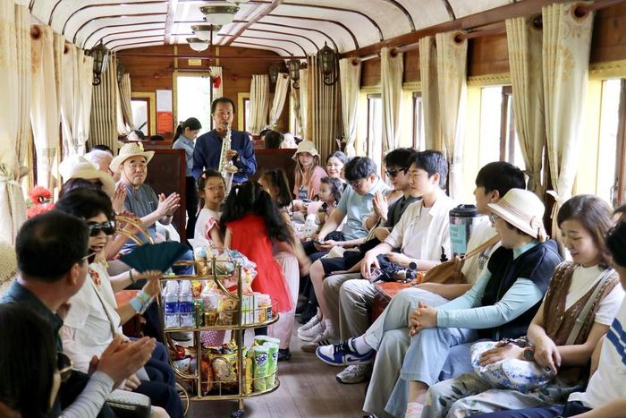 Biểu diễn âm nhạc phục vụ du khách trên chuyến tàu từ Ga Đà Lạt đến Ga Trại Mát (Lâm Đồng). Ảnh: TTXVN