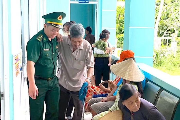 Cán bộ Đồn Biên phòng Đất Mũi hỗ trợ người dân đi lại khó khăn được đến nơi khám mắt. (Ảnh: HOÀNG TÁ)
