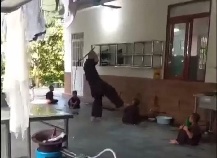 Người đàn ông đánh trẻ bằng roi. (Ảnh cắt từ clip)