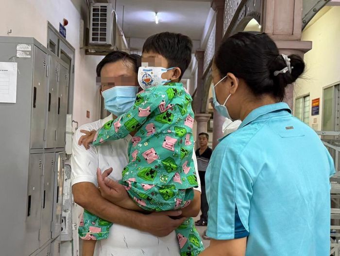 Trước giờ xuất viện, người cha vẫn chưa quen với hình ảnh con trai có thể tự chạy nhảy nên bế bé lên. Ảnh: Thanh Huyền