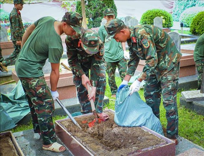 Lực lượng tham gia dùng xẻng và các dụng cụ chuyên dụng để khai quật phần mộ liệt sĩ.