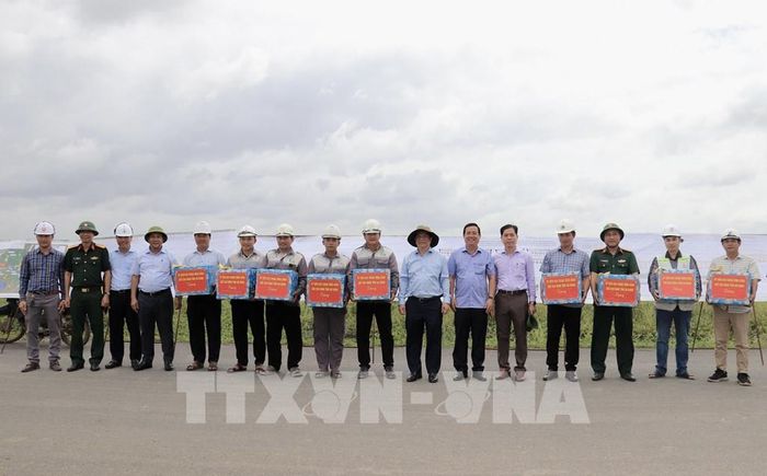 Ông Hồ Văn Mừng, Chủ tịch UBND tỉnh An Giang (thứ 7 từ bên phải qua) tặng quà cho các công nhân trên công trường thi công cao tốc tại nút giao với Đường tỉnh 943, xã Định Mỹ. Ảnh: Thanh Sang-TTXVN