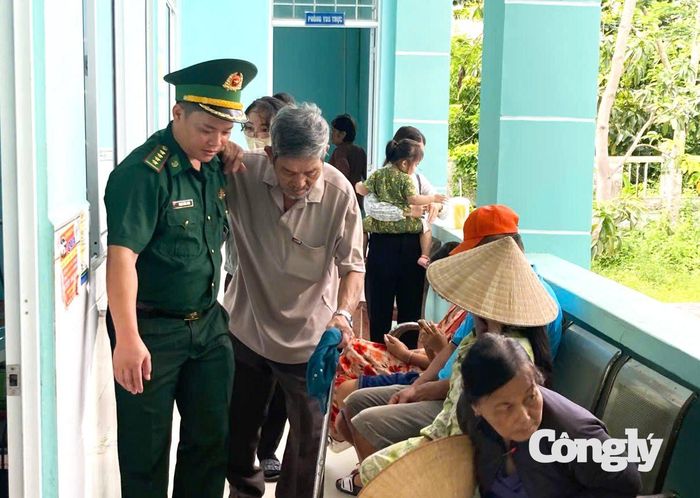 Cán bộ đồn Biên phòng Đất Mũi hỗ trợ người dân đi lại khó khăn được đến nơi khám mắt