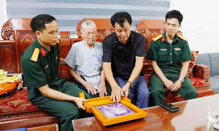  Bà Nguyễn Thị Bẩy (thứ hai bên trái) xem di ảnh của con trai đã hy sinh. 