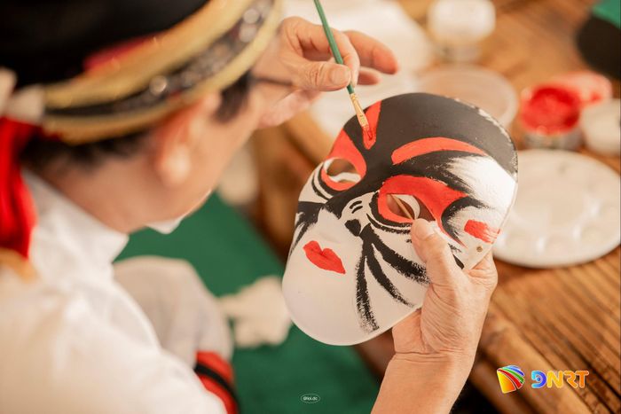 Du khách trải nghiệm vẽ mặt nạ tuồng. Ảnh: AHT