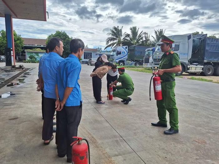  Lực lượng chức năng hướng dẫn cán bộ, nhân viên cửa hàng cách dùng bình chữa cháy cầm tay. Ảnh: ĐVCC 