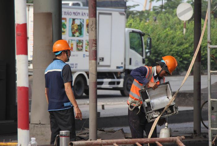 Công việc diễn ra ngay trên tuyến QL1 nên các khâu tháo dỡ được triển khai thận trọng, đảm bảo an toàn. Máy móc hoạt động liên tục bên trong công trường, trong khi bên ngoài, các phương tiện vẫn di chuyển qua tuyến đường.