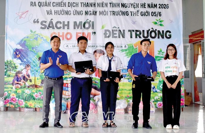 Chủ tịch Uỷ ban MTTQ Việt Nam xã Vĩnh Lợi Hà Phú Quí (bên trái) trao tặng máy vi tính xách tay cho học sinh có hoàn cảnh khó khăn từ nguồn vận động.