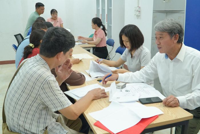 Ông Nguyễn Xuân Hồng (áo trắng), Tổ trưởng Tổ dân phố 41, hướng dẫn người dân rà soát, đối chiếu thông tin đất đai. Ảnh: Tùng Lâm