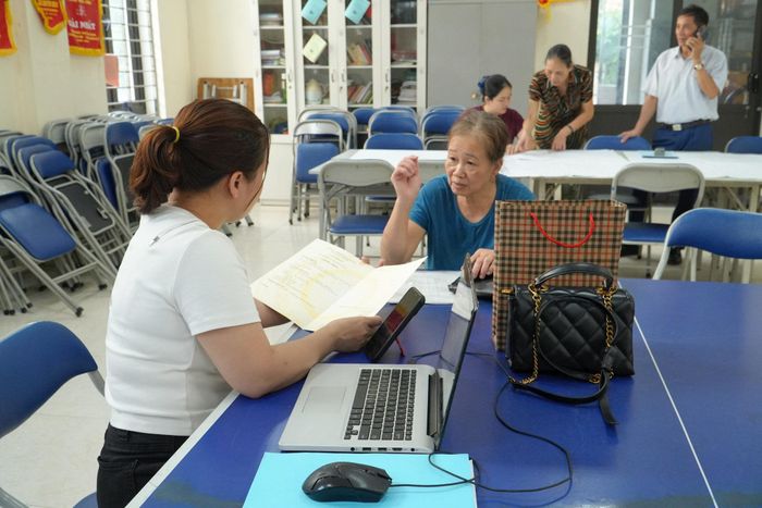 Người dân được cán bộ hướng dẫn đối chiếu giấy tờ, cập nhật dữ liệu đất đai. Ảnh: Tùng Lâm