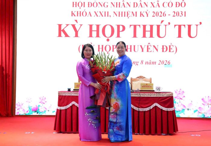 Tân Chủ tịch UBND xã Cổ Đô Nguyễn Thị Nam (bên trái) đón nhận hoa chúc mừng của Bí thư Đảng ủy, Chủ tịch HĐND xã Nguyễn Thị Kim Oanh. Ảnh: Hồng Đạt