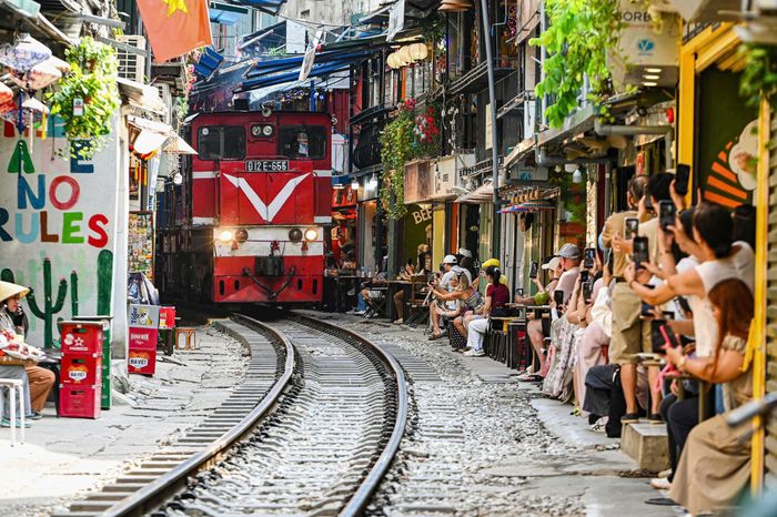 Khi tàu đi qua, dù ngồi sát mép tường nhưng du khách vẫn trong phạm vi nguy hiểm, vi phạm hành lang an toàn đường sắt. (Ảnh HQ)