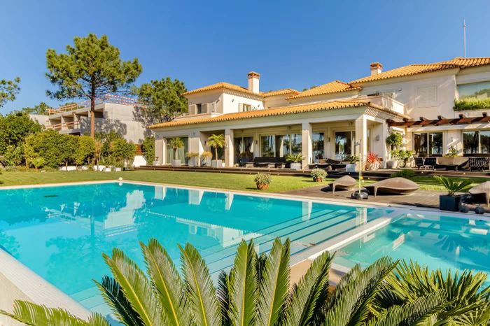  Căn biệt thự của Ronaldo và Georgina nằm trên khu đất rộng hơn 12.000 m², với diện tích xây dựng gần 5.000 m². Ban đầu được dự định làm nơi nghỉ dưỡng, căn nhà sau đó trở thành nơi ở lâu dài của gia đình tại Bồ Đào Nha. Những ô cửa sổ lớn hướng ra Đại Tây Dương, tận dụng ánh sáng tự nhiên và cảnh quan bên ngoài. Công trình có hai hồ bơi, phòng gym, spa, phòng chiếu phim và khu vườn rộng. Trong ảnh là một căn biệt thự rộng hơn 9.600 feet vuông (khoảng 893 m²) nằm trong cùng khu vực. Ảnh: Irglux - Fine & Country Portugal. 
