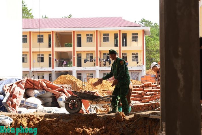 Cán bộ, chiến sĩ Đồn Biên phòng cửa khẩu Chi Ma xếp gạch tại khu vực tập kết, tạo thuận lợi cho các tổ thợ sử dụng trong quá trình thi công. Ảnh: Khánh Chi
