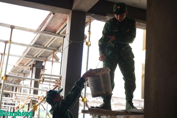 Bên trong các khối nhà, cán bộ, chiến sĩ Biên phòng hỗ trợ vận chuyển vữa và vật liệu đến từng vị trí, góp sức cùng công nhân đẩy nhanh tiến độ hoàn thiện công trình. Ảnh: Khánh Chi