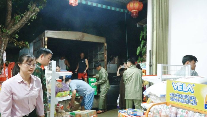 Các hộ gia đình kinh doanh được lực lượng chức năng hỗ trợ di chuyển hàng hóa đến nơi an toàn. Ảnh: XQS