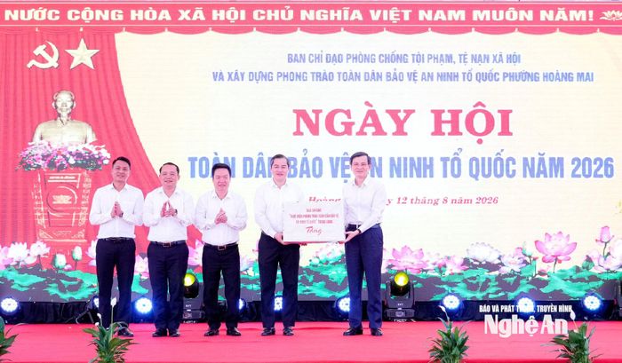 Đồng chí Đoàn Minh Huấn - Ủy viên Bộ Chính trị, Giám đốc Học viện Chính trị quốc gia Hồ Chí Minh tặng quà cho Đảng bộ, chính quyền và Nhân dân phường Hoàng Mai. Ảnh: Phạm Bằng