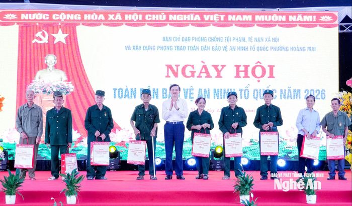 Đồng chí Đoàn Minh Huấn - Ủy viên Bộ Chính trị, Giám đốc Học viện Chính trị quốc gia Hồ Chí Minh tặng quà cho các hộ dân trên địa bàn phường Hoàng Mai. Ảnh: Phạm Bằng