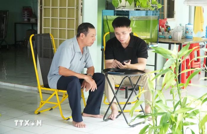 Các thành viên Tổ công nghệ số cộng đồng hướng dẫn người dân thực hiện dịch vụ công trực tuyến. (Ảnh: Hữu Duyên/TTXVN)