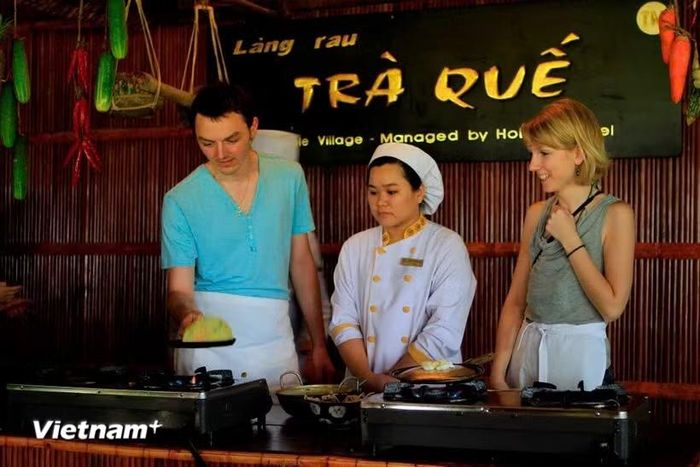 Du khách quốc tế trải nghiệm làm bánh xèo sau khi hái rau ở Làng rau Trà Quế, Hội An. (Ảnh: Xuân Mai/Vietnam+)