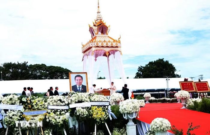 Gia quyến đồng chí Xaysomphone Phomvihane thực hiện nghi thức tưới nước cầu siêu thoát. (Ảnh: Xuân Tú/TTXVN)