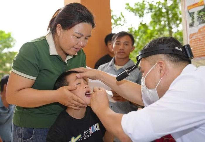 Bác sĩ khám tai, mũi, họng cho trẻ em trong chương trình khám, tư vấn sức khỏe miễn phí. Ảnh: TTXVN phát