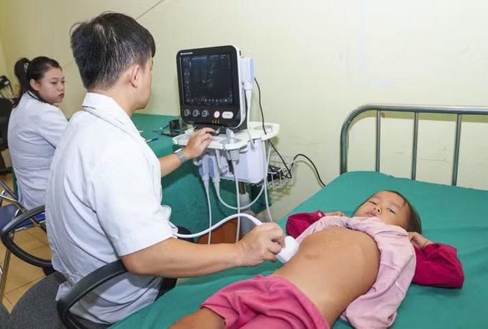 Bác sĩ thực hiện siêu âm cho trẻ em bằng thiết bị siêu âm lưu động, phục vụ công tác khám sức khỏe định kỳ cho người dân. Ảnh: TTXVN phát