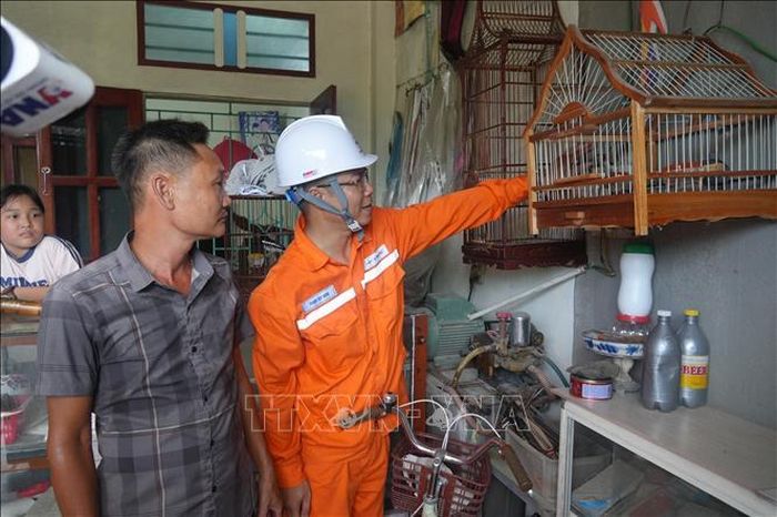 Cán bộ điện lực hướng dẫn gia đình ông Nguyễn Hữu Duyên di dời toàn bộ vật dễ cháy cách xa ổ điện tối thiểu 0.5m cũng như các biện pháp phòng tránh tai nạn điện, cách sử dụng điện an toàn, tiết kiệm và hiệu quả. Ảnh: Hoa Mai/TTXVN