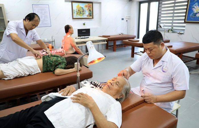 Nhân viên y tế đang xoa bóp, bấm huyệt cho người cao tuổi.