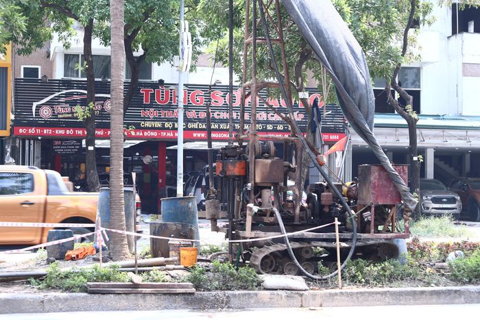 Tại đường Văn Khê, có 6 lỗ khoan nằm giữa dải phân cách, đoạn từ ngõ 24 Văn Phú đến nhà số 4 phố Văn Khê. Hai lỗ khoan còn lại được bố trí tại khu vực dải phân cách bị thu hẹp. Đường kính khoan tối đa 152mm, đường kính cần khoan 42mm (Trong ảnh công nhân đang triển khai máy móc, thiết bị khoan xuống lòng đường để lấy mẫu, thu thập các thông số địa chất). Theo anh Mai Thanh Nam, Công ty Cầu lớn - Hầm cho biết: "Công tác khoan khảo sát nhằm thu thập các thông số kỹ thuật cần thiết, phục vụ việc thiết kế và triển khai xây dựng hạ tầng, đặc biệt là các hạng mục trụ cầu vượt. Việc khảo sát địa chất được xem là bước quan trọng trước khi triển khai thiết kế chi tiết và thi công các hạng mục cầu, đường dẫn, giúp xác định điều kiện nền đất, từ đó đưa ra phương án xử lý móng và kết cấu công trình phù hợp".