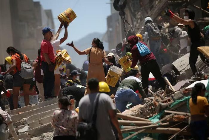 Người dân tạo thành những dây chuyền người để vận chuyển đất đá. Ảnh Reuters.
