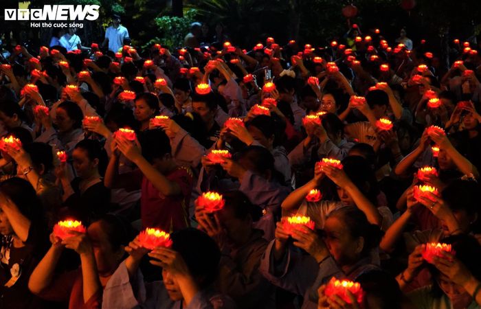 Hàng nghìn phật tử dâng những đóa hoa sen đỏ thắm trên đầu dịp lễ Vu Lan. (Ảnh: Mạnh Hiếu)
