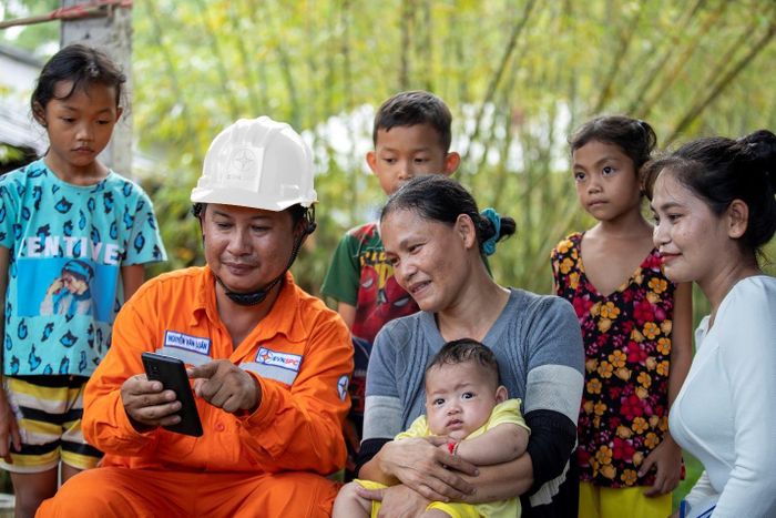 Công nhân ngành Điện tuyên truyền tiết kiệm điện đến người dân. Ảnh: Ngọc Tuấn