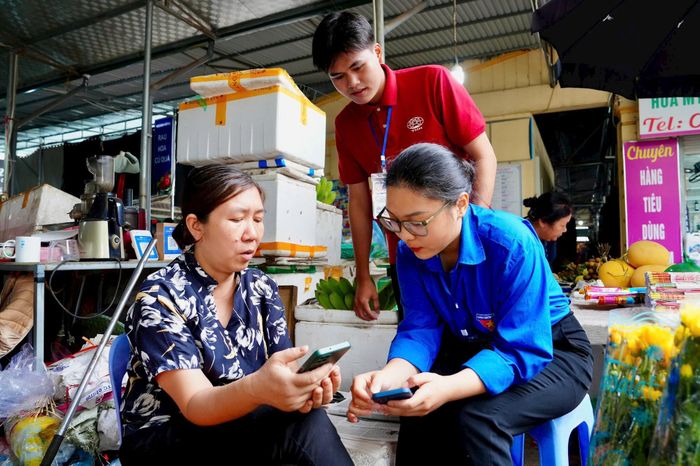 Đoàn viên thanh niên phường Phú Thượng hướng dẫn người dân thực hiện chuyển đổi số. Ảnh: PV
