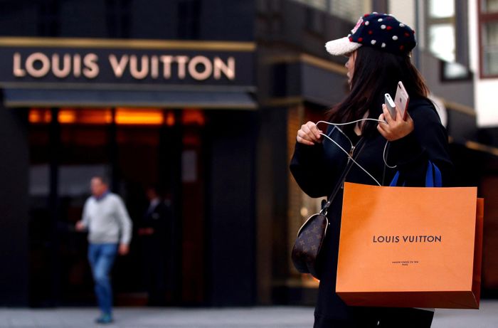  Một người phụ nữ cầm túi mua sắm hiệu Louis Vuitton. Ảnh: Reuters. 