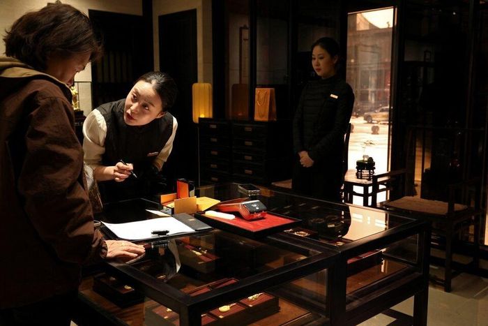 Một nhân viên phục vụ khách hàng tại cửa hàng trang sức Laopu Gold ở Bắc Kinh. Ảnh: Reuters. 