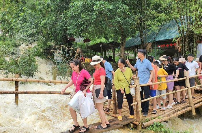 Du khách trải nghiệm cầu tre bắc qua dòng suối tại khu du lịch thác Mây. Ảnh: Nguyễn Linh